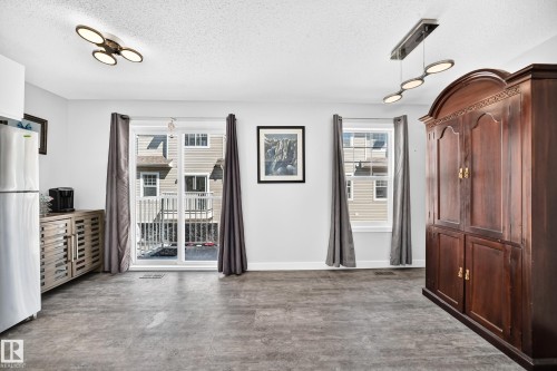 Spacious interior featuring a sliding glass door, a separate window, wood-finish flooring, and contemporary overhead lighting - 146 5604 199 Street, Edmonton, AB 
