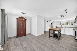 Open-concept living space featuring wood-finish flooring, a modern linear chandelier, recessed lighting, and track lighting - 