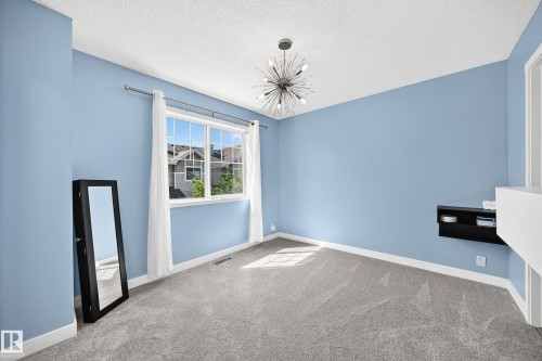 Room featuring a textured ceiling, a contemporary sputnik chandelier, and light blue walls with white trim - 146 5604 199 Street, Edmonton, AB 
