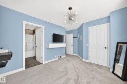 Spacious room featuring light blue walls, gray carpeting, and a contemporary sputnik-style ceiling fixture - 