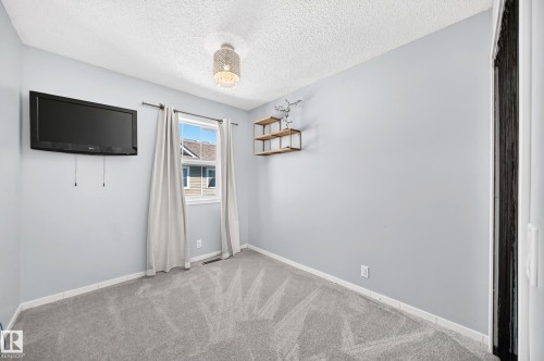 Carpeted interior room featuring light gray walls, a single window, and a ceiling-mounted light fixture - 146 5604 199 Street, Edmonton, AB 