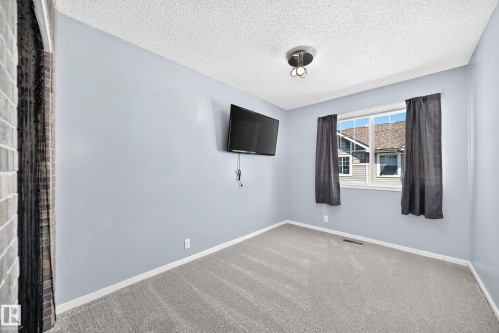 Bedroom featuring light blue walls, gray carpeting, and a window with white trim - 146 5604 199 Street, Edmonton, AB 