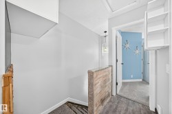 Hallway featuring wood-finish flooring, a stone-accented half-wall, and a contemporary pendant light fixture - 