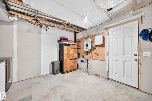 Utility room featuring a paneled door, exposed ceiling joists, and concrete flooring - 146 5604 199 Street, Edmonton, AB 