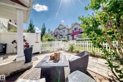Private patio space featuring a paved surface, white picket fencing, and surrounding landscaping - 