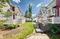 Exterior walkway featuring concrete steps, a black metal handrail, and white picket fencing - 