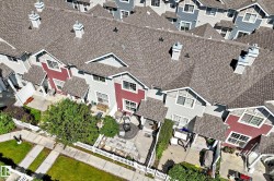Aerial perspective highlighting a row of townhouses featuring gabled roofs with asphalt shingles, contrasting siding colors, and individual outdoor patio spaces - 