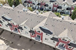 Multi-story townhomes featuring asphalt shingle roofing, attached garages, and private balconies - 