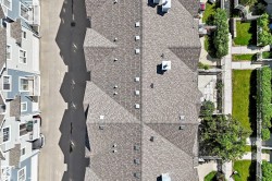 Residential building featuring shingle roofing, multiple chimneys, and various vents - 