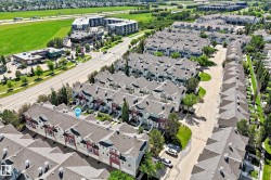 Aerial perspective showcasing a community of multi-story townhomes with pitched roofs and individual garages - 