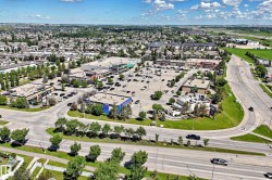 Aerial overview of a commercial development featuring multiple retail buildings and extensive paved parking areas - 