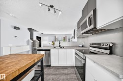 Modern kitchen featuring two-tone cabinetry, stainless steel appliances, and wood-finish flooring - 