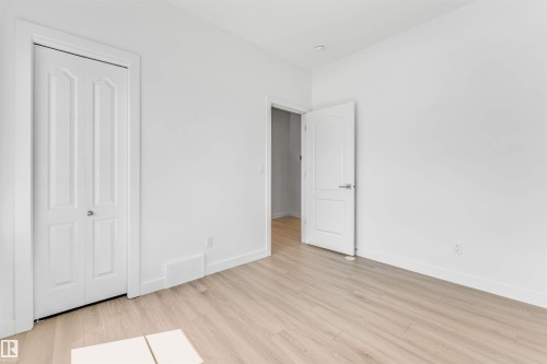 Bright room featuring wood-finish flooring, white walls, a bi-fold closet door, and a recessed ceiling light - 1208 14 Ave Nw, Edmonton, AB 