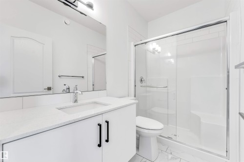 Bathroom featuring a white vanity with a light-toned countertop, an undermount sink with a chrome faucet, and a large mirror - 1208 14 Ave Nw, Edmonton, AB 