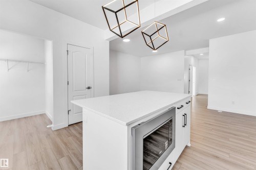 Kitchen island with a white countertop and integrated microwave drawer, complemented by geometric pendant lighting - 1208 14 Ave Nw, Edmonton, AB 