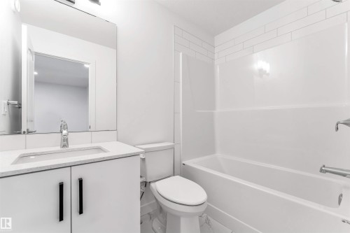 Bathroom featuring a white vanity with quartz countertop, integrated sink, and black hardware - 1208 14 Ave Nw, Edmonton, AB 