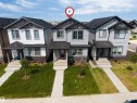 Modern townhouse exterior featuring light grey siding, dark trim, and a prominent front entrance with an overhang - 1208 14 Ave Nw, Edmonton, AB 