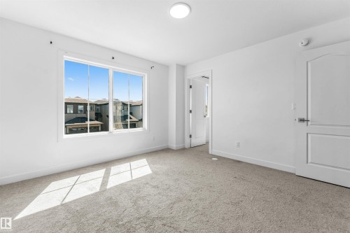 Bright room featuring a large multi-pane window, flush-mount ceiling light, and light-toned carpeting - 1208 14 Ave Nw, Edmonton, AB 