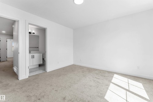 Carpeted room featuring a white wall finish and a ceiling-mounted light fixture - 1208 14 Ave Nw, Edmonton, AB 