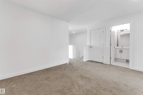 Carpeted hallway with a staircase, recessed lighting, and a white interior door - 1208 14 Ave Nw, Edmonton, AB 