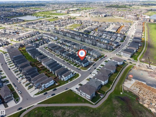Aerial perspective showcasing a developed residential community with diverse housing styles, paved roadways, and a prominent water feature - 1208 14 Ave Nw, Edmonton, AB 