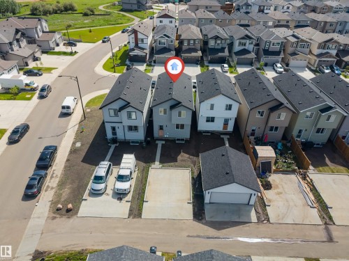 Modern detached home featuring a dark shingle roof, light grey siding, and a white garage door - 1208 14 Ave Nw, Edmonton, AB 