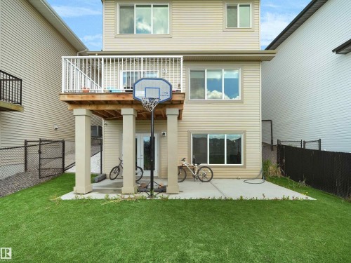 Rear exterior featuring vinyl siding, an elevated deck with white railings, a ground-level concrete patio, and a grass lawn - 4615 175 Avenue, Edmonton, AB 