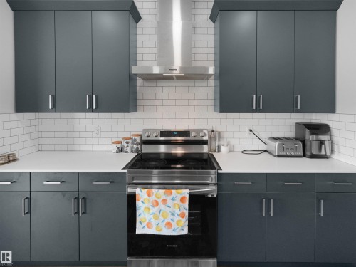 Modern kitchen featuring a stainless steel range with a coordinating range hood - 4615 175 Avenue, Edmonton, AB 