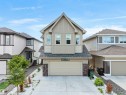 Modern two-story residence featuring light beige vertical and horizontal siding, a prominent front-facing gable, and stone veneer accents - 4615 175 Avenue, Edmonton, AB 