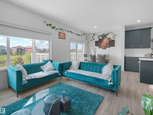 Open-concept living area featuring wood-finish flooring and ample natural light from large windows - 4615 175 Avenue, Edmonton, AB 