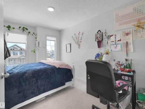 Bright bedroom featuring two windows with roller shades, recessed ceiling lighting, and light-toned carpet flooring - 4615 175 Avenue, Edmonton, AB 