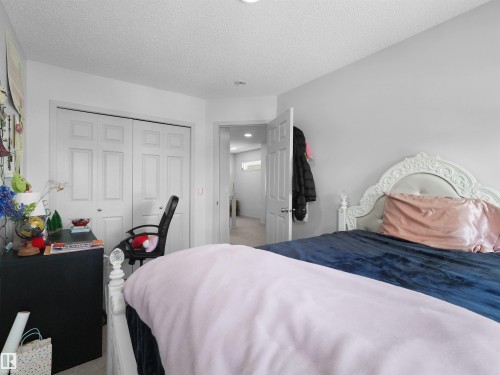 Bedroom featuring neutral painted walls, textured ceiling, and white bifold closet doors - 4615 175 Avenue, Edmonton, AB 