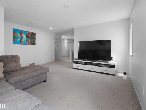 Carpeted living area featuring light-toned walls, recessed ceiling lighting, and a visible window - 4615 175 Avenue, Edmonton, AB 