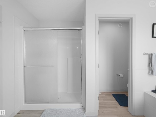 Full shower enclosure with a sliding frosted glass door and white interior paneling - 4615 175 Avenue, Edmonton, AB 