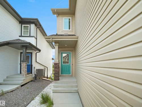 Modern exterior with light-toned horizontal siding and a vibrant teal entry door - 4615 175 Avenue, Edmonton, AB 