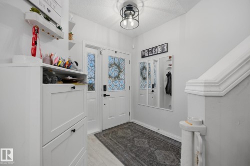 Entryway featuring a white door with decorative glass inserts, a coordinating sidelight, and a modern black ceiling light fixture - 60 Leyland Way, Spruce Grove, AB 