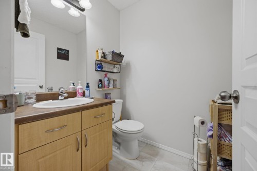 Bathroom vanity with a wood-finish cabinet, integrated sink, and dark countertop - 60 Leyland Way, Spruce Grove, AB 