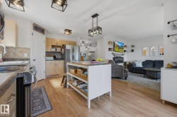 Open-concept kitchen and living area featuring wood-finish flooring, recessed lighting, and a kitchen island with open shelving - 