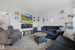 Living space featuring an electric fireplace with a wood mantle, white walls, and a ceiling-mounted light fixture - 