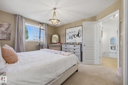 Carpeted room featuring a single window with outdoor greenery, a ceiling-mounted light fixture, and an open doorway revealing an additional space - 