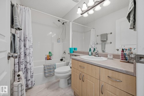 Full bathroom featuring a single vanity with wood-finish cabinetry, an oval undermount sink, and a laminate countertop - 60 Leyland Way, Spruce Grove, AB 