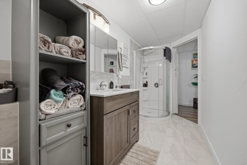 Contemporary bathroom featuring a wood-finish vanity with a white countertop and rectangular undermount sink - 60 Leyland Way, Spruce Grove, AB 