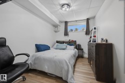 Bedroom featuring wood-finish flooring, a drop ceiling, and a flush-mount light fixture - 