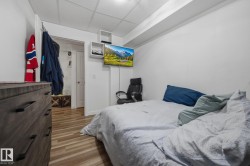 Compact room featuring wood-finish flooring, white walls, and a drop-ceiling - 