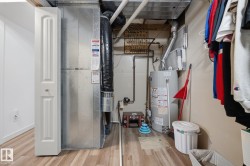 Utility area with wood-finish flooring, a water heater, and a furnace unit - 