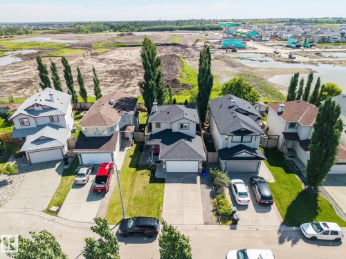 Residential street featuring single-family homes with attached garages, paved driveways, and manicured front lawns - 60 Leyland Way, Spruce Grove, AB 