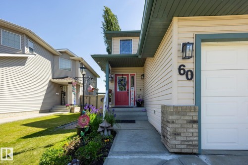 Cream-colored siding facade with a contrasting dark green soffit and trim - 60 Leyland Way, Spruce Grove, AB 