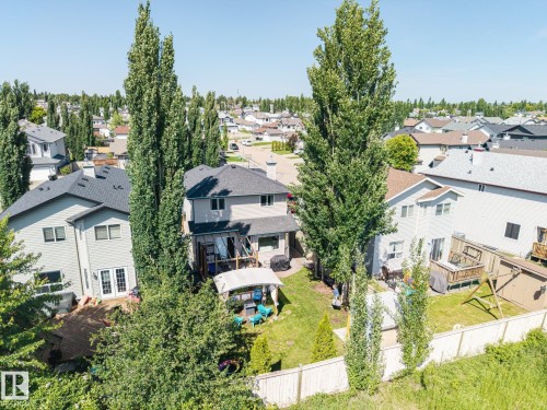 Private backyard featuring a light-toned wooden fence, mature trees, and a wooden deck - 60 Leyland Way, Spruce Grove, AB 