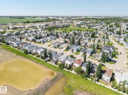 Aerial perspective of a residential neighborhood featuring detached homes with varied rooflines and a mix of mature and young trees - 