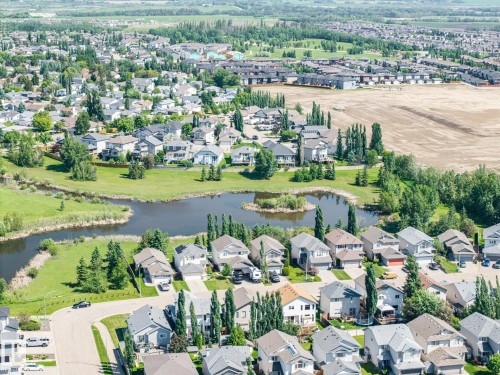 Residential development featuring a large pond with an island, surrounded by green spaces and mature trees - 60 Leyland Way, Spruce Grove, AB 